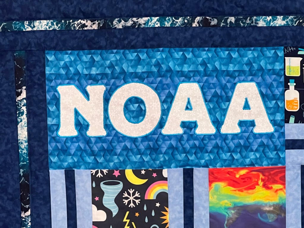 Photo of quilt zoomed in on the upper-left corner that says NOAA
