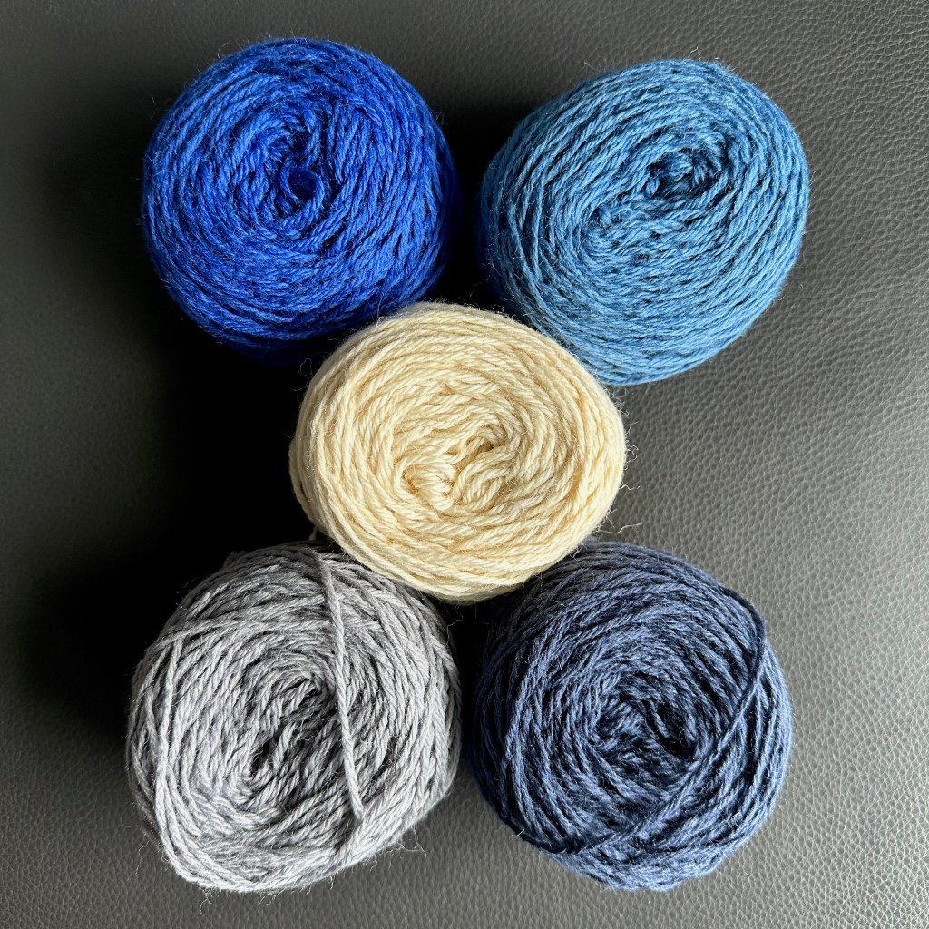 Five balls of yarn - two shades of blue, one cream, two shades of gray