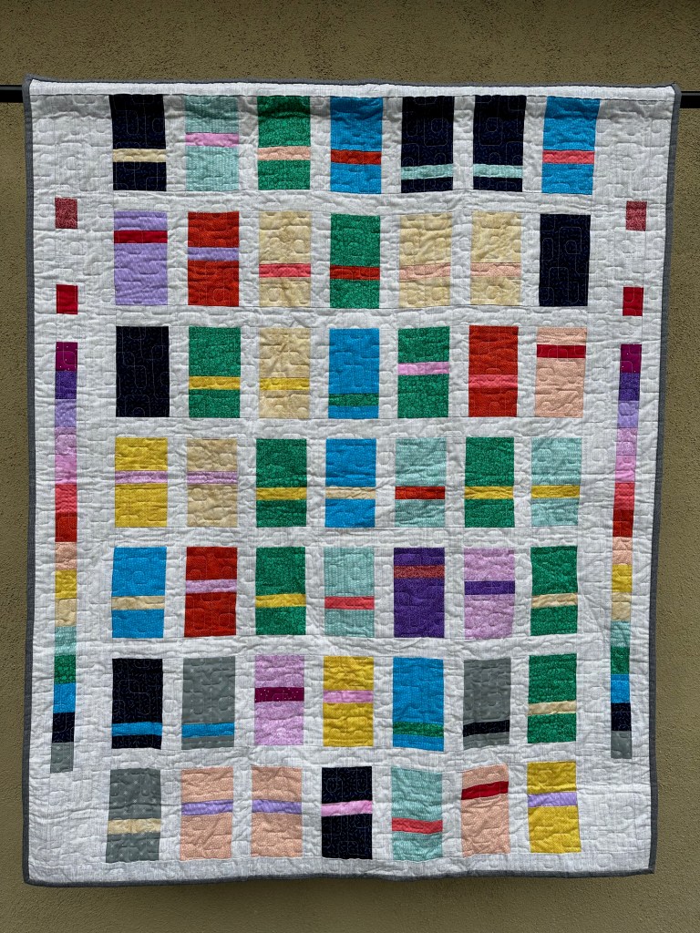 Photo of hanging quilt with rectangles of many colors