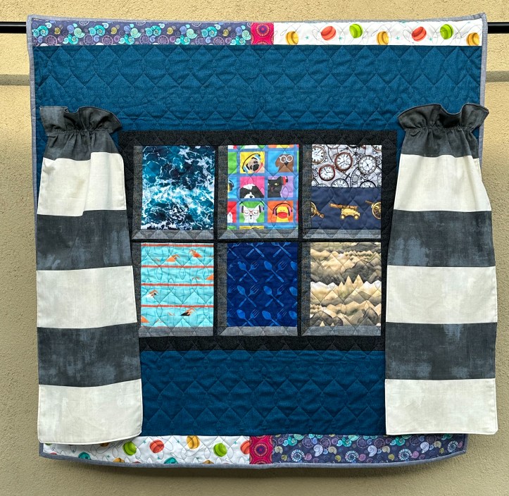 Photo of hanging quilt, designed as a window with curtains