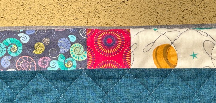 Top border of hanging quilt with three different fabrics