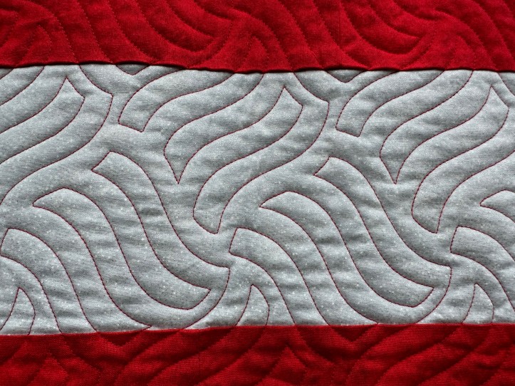Close-up of silver stripe of fabric in red background