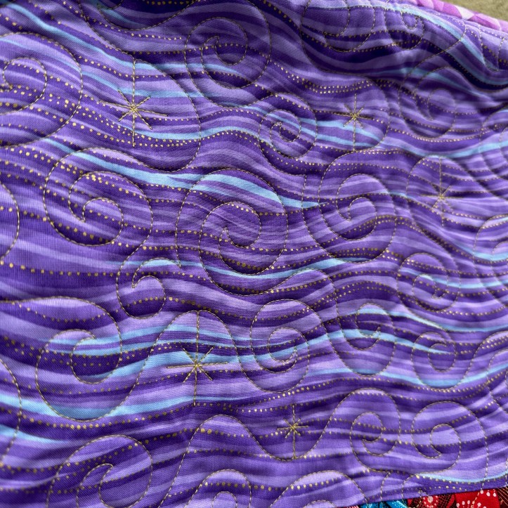 Gold star stitching on front of hanging quilt