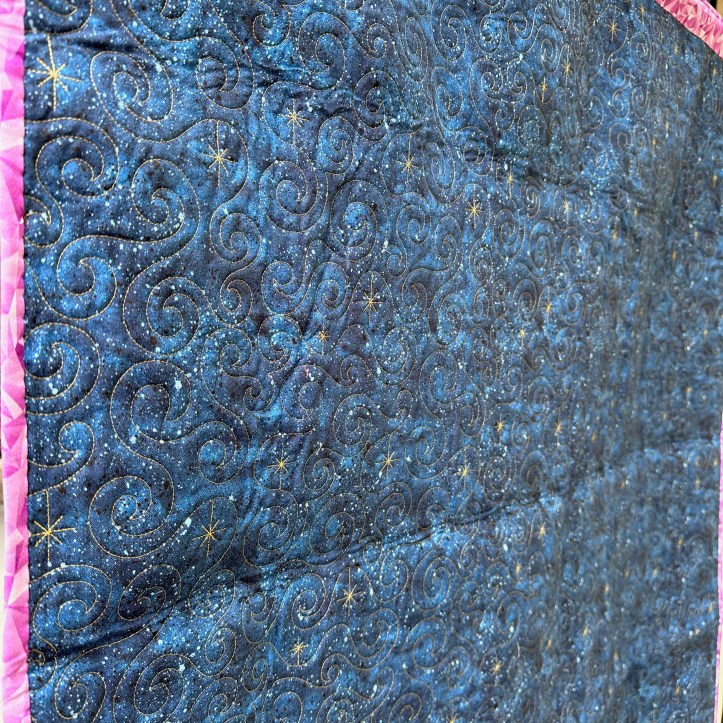 Back of hanging quilt, showing gold star stitching on blue background