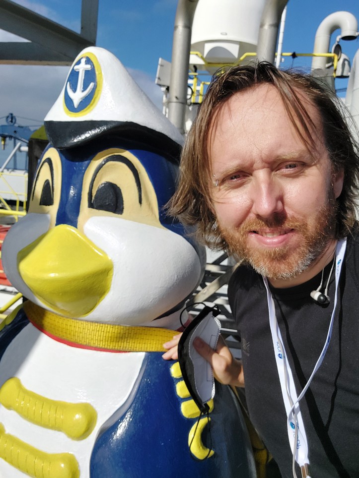 selfie of person next to head of penguin statue