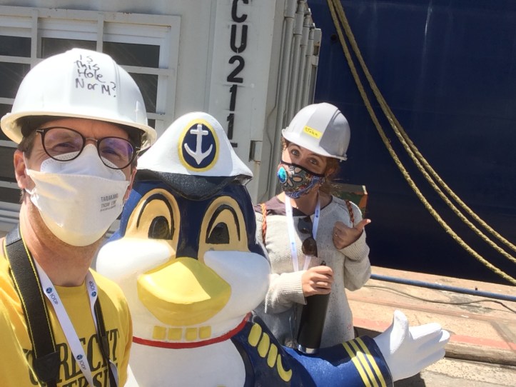 two people wearing masks and hardhats next to penguin statue