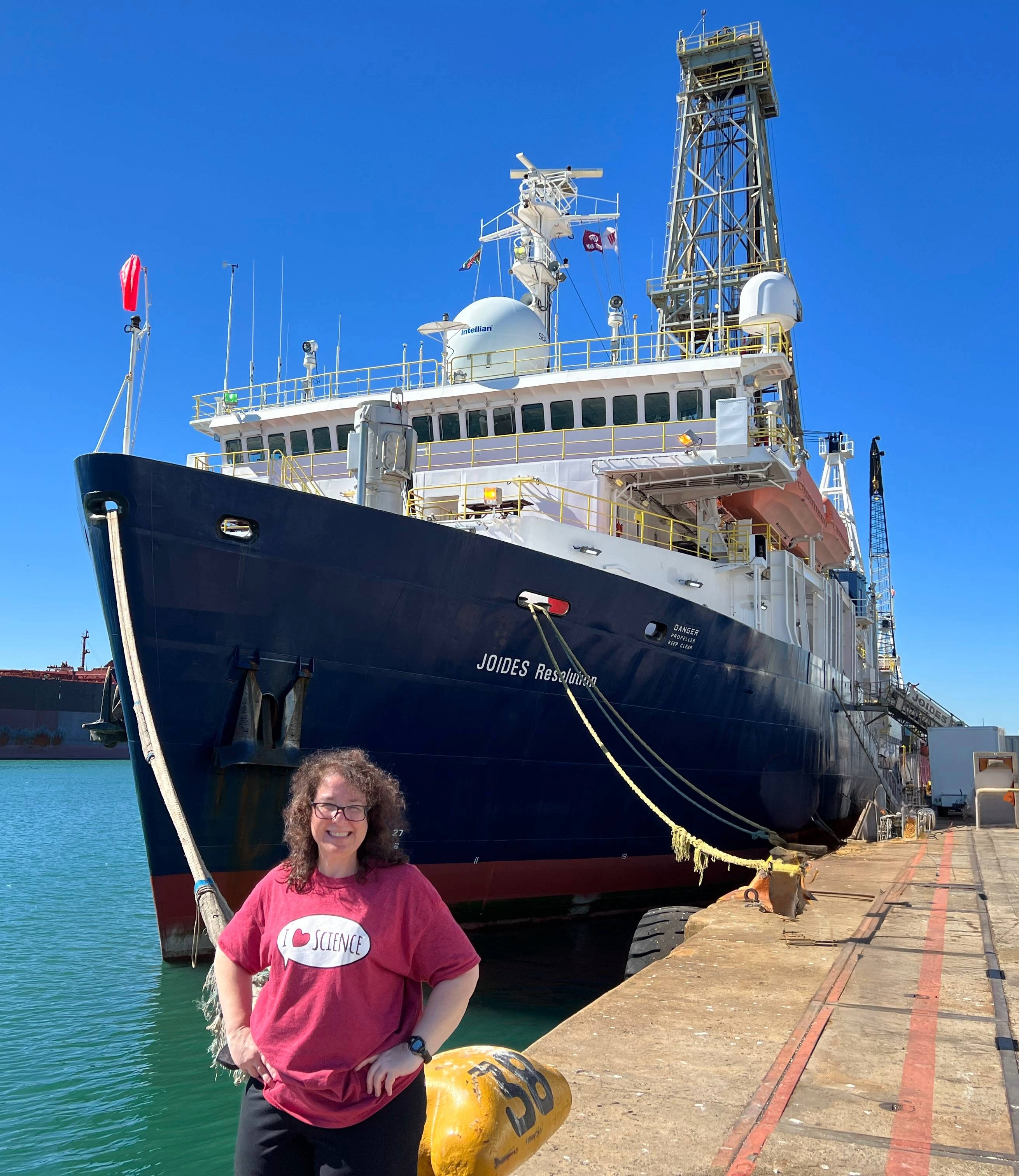 person standing in front of a scientific drilling vessel while the ship is docked