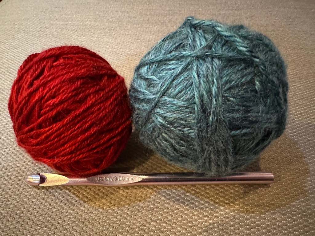 Two balls of yarn (one red, one blue) and a crochet hook
